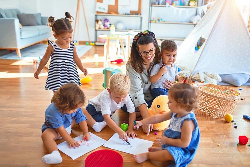 A teacher playing with young children in a classroom.